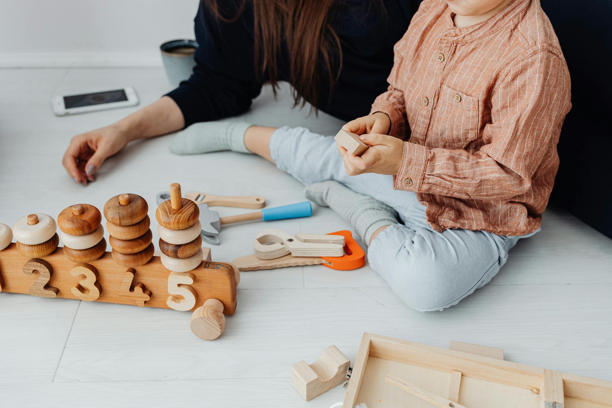 Child plays with educational wooden toys indoors, promoting learning and creativity.